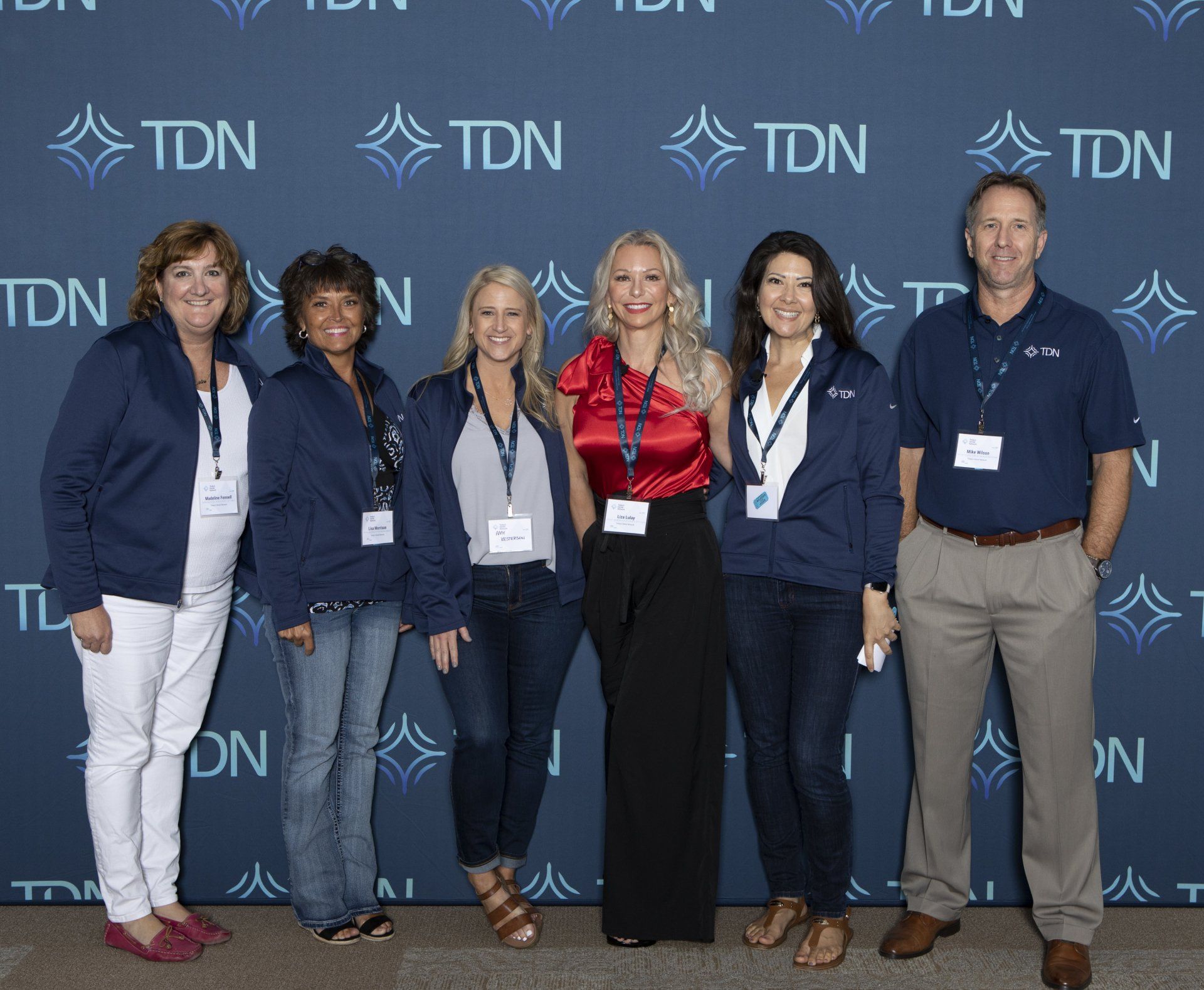 A group of people standing in front of a wall that says tdn