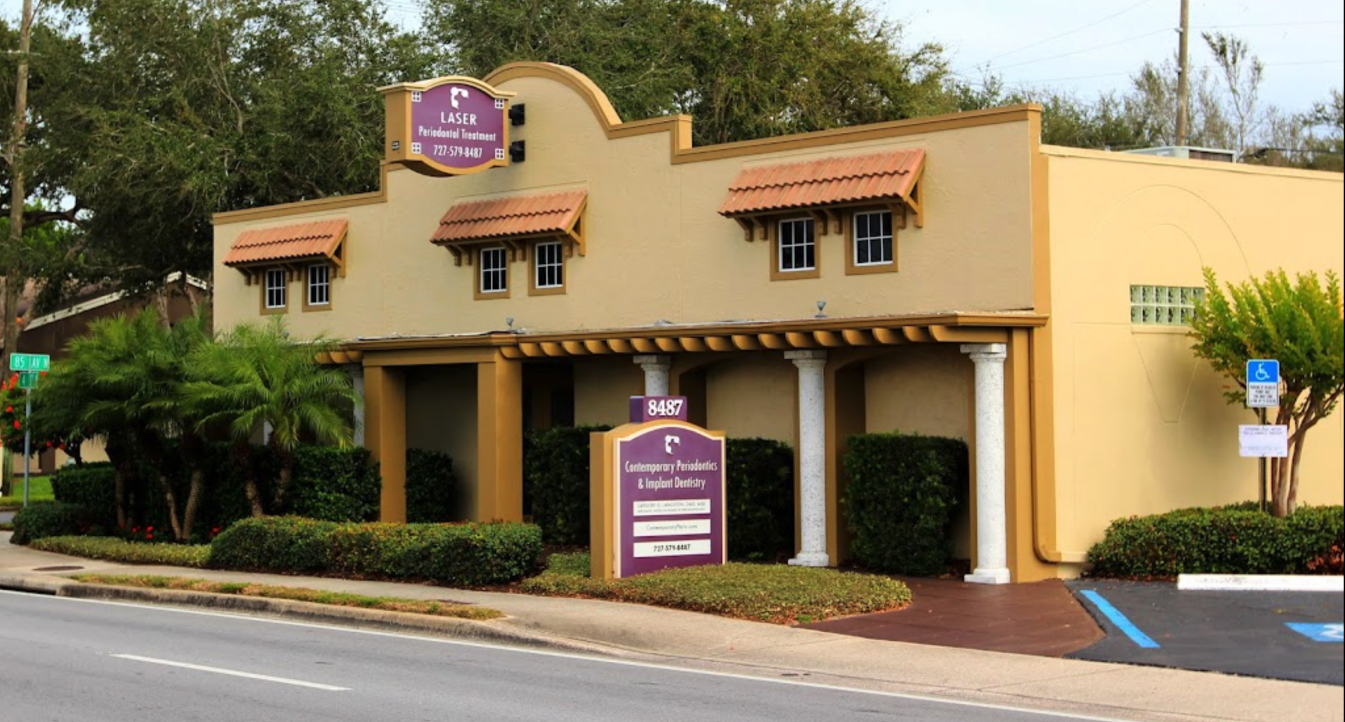 A yellow building with a purple sign in front of it