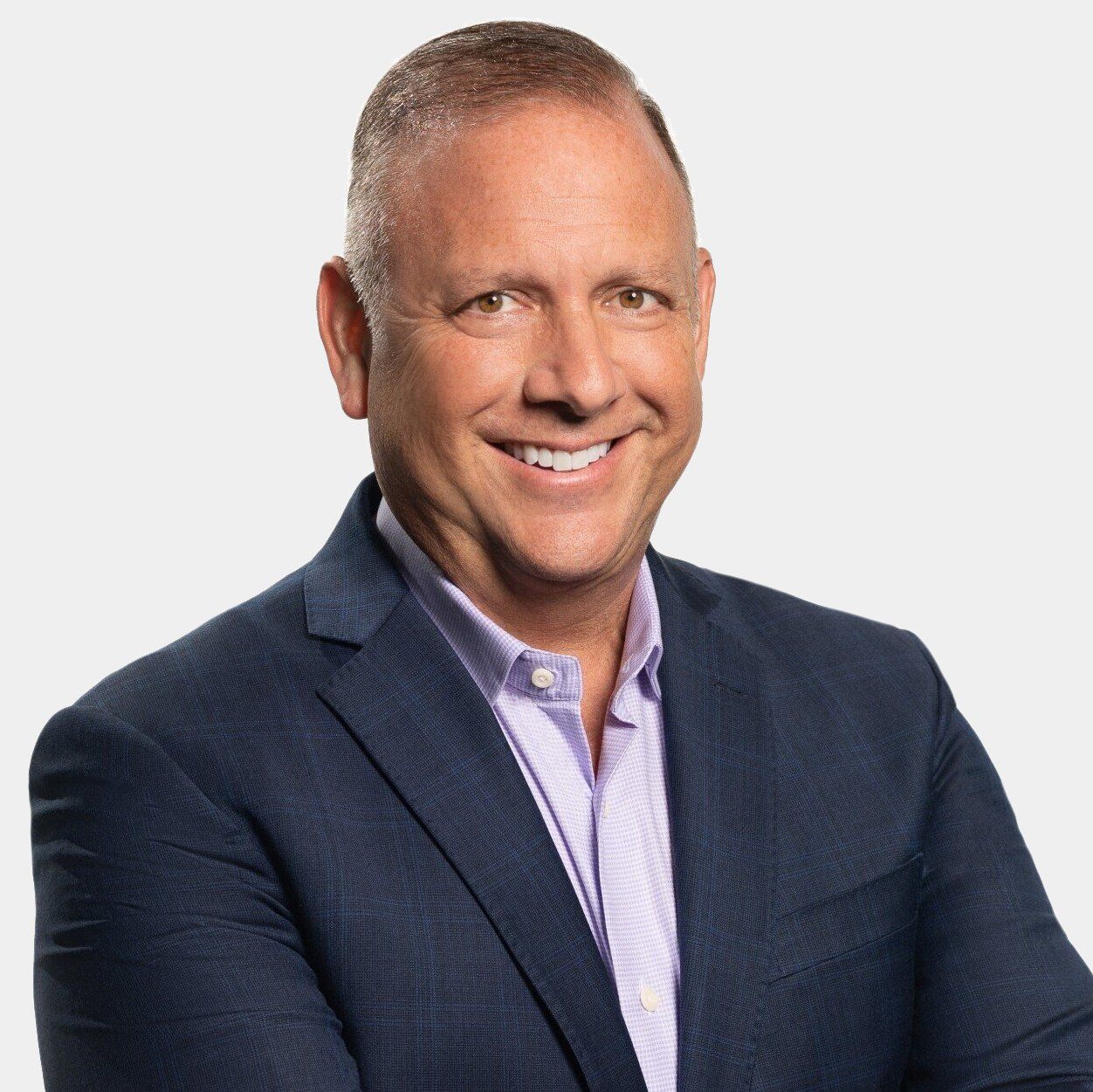 A man in a suit and purple shirt is smiling for the camera.