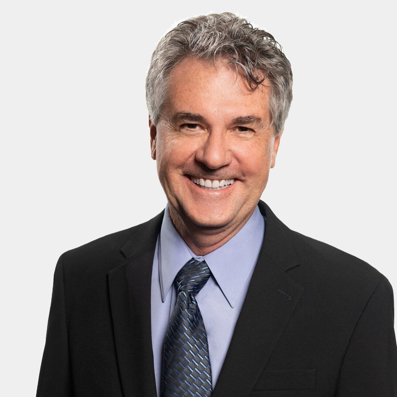A man in a suit and tie is smiling for the camera.