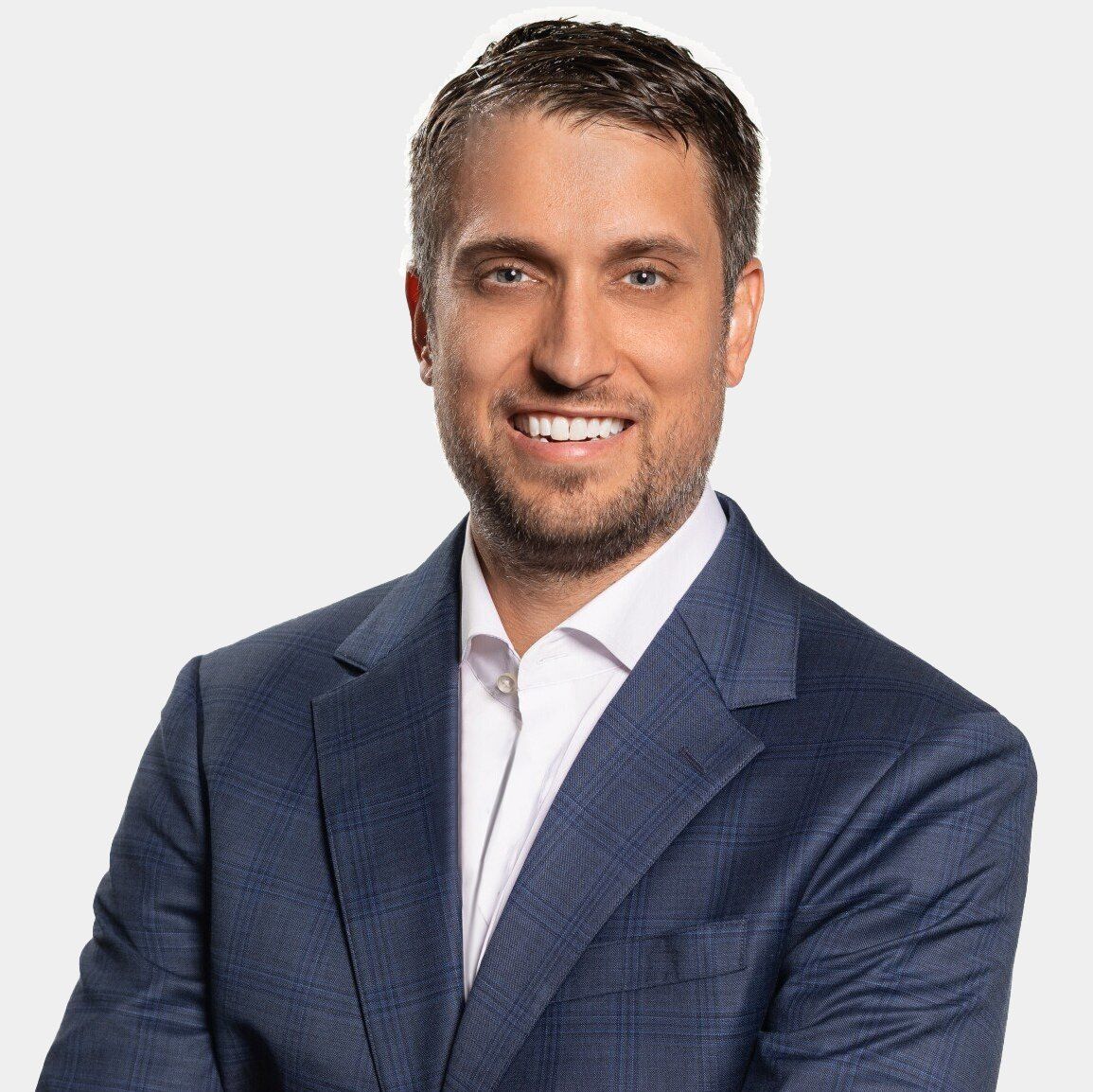 A man in a blue suit and white shirt is smiling for the camera.