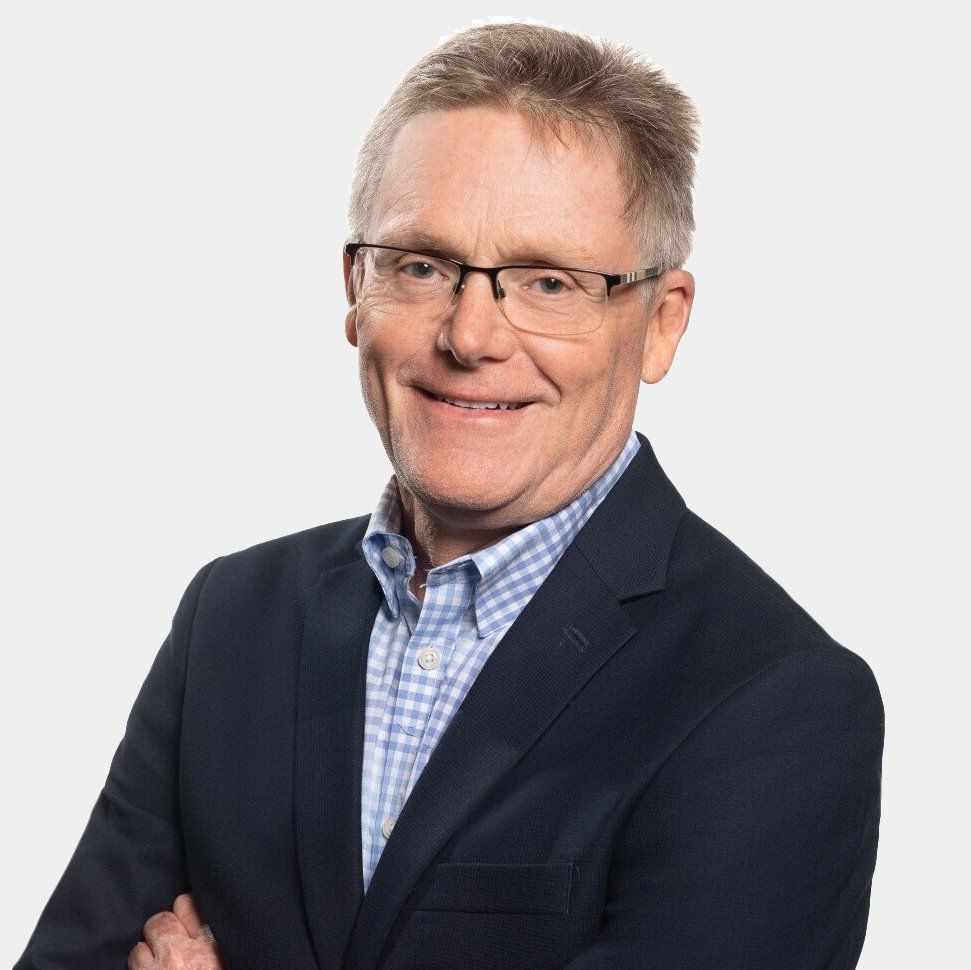A man in a suit and glasses is smiling for the camera.