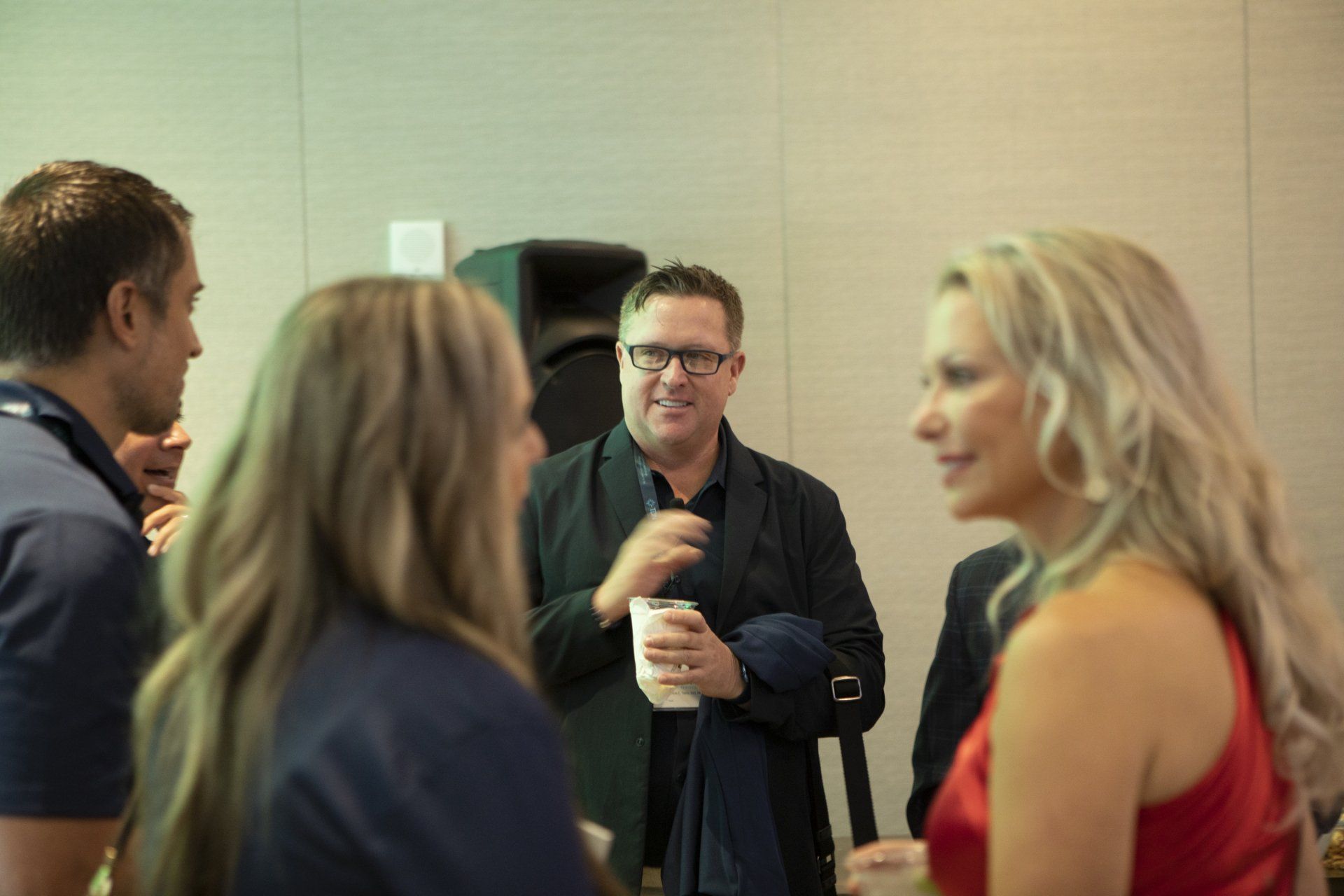 A group of people are standing around talking to each other in a room.