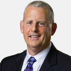 A man in a suit and tie is smiling for the camera.