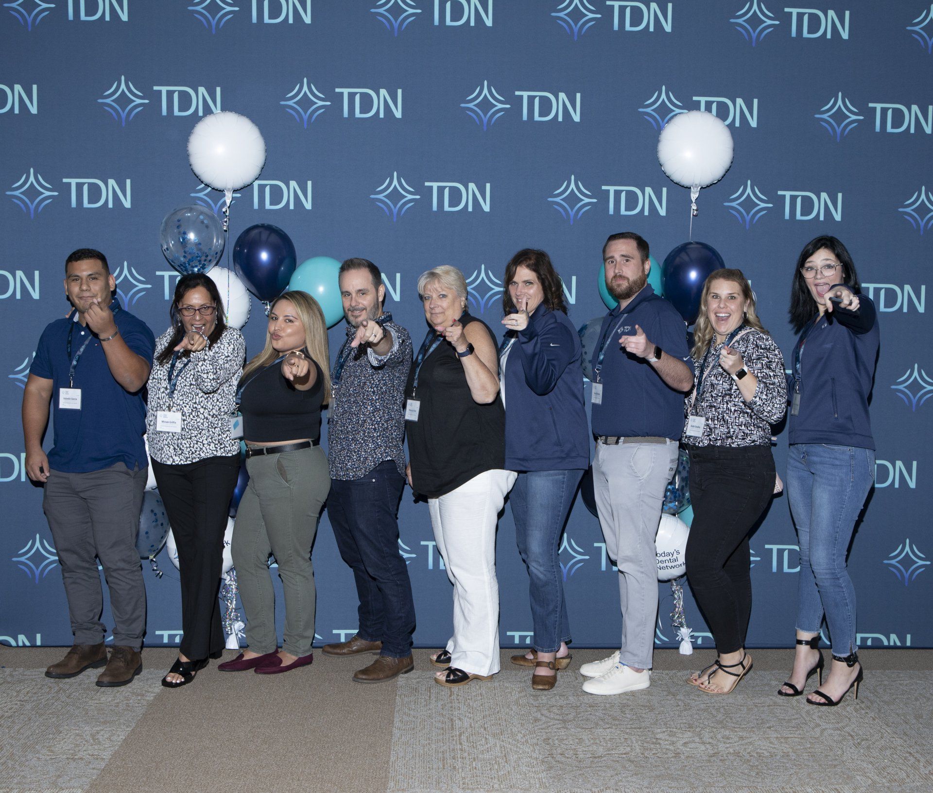 A group of people standing in front of a wall that says tdn