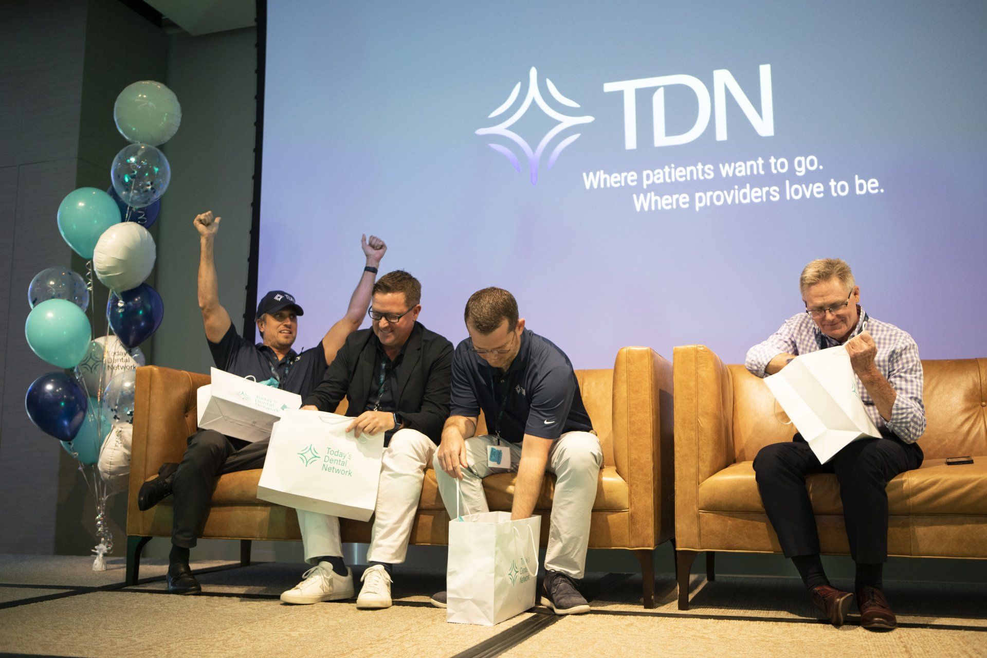 A group of men are sitting on a couch in front of a tdn logo.