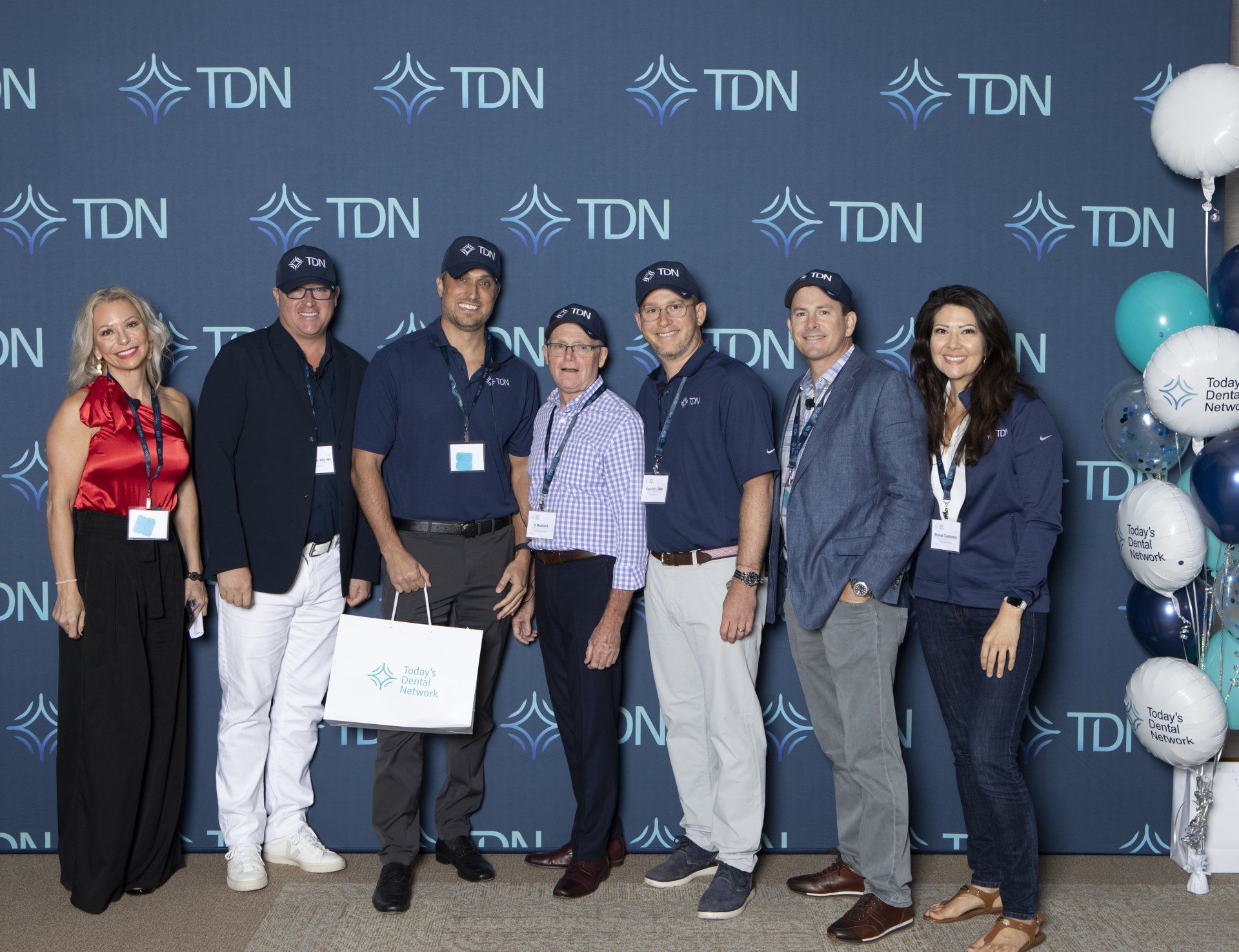 A group of people standing in front of a blue wall that says tdn