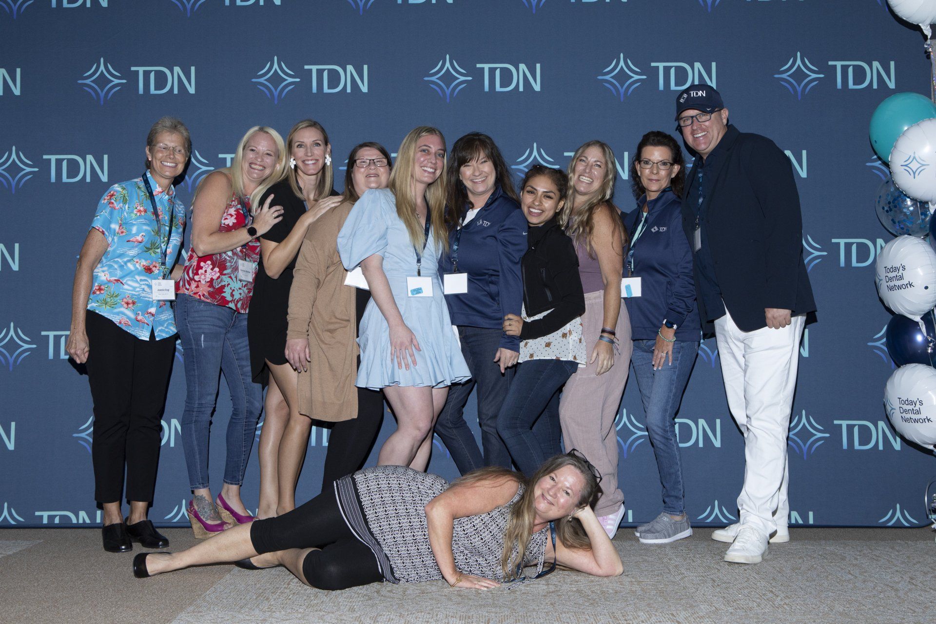 A group of people are posing for a picture in front of a wall that says tdn.