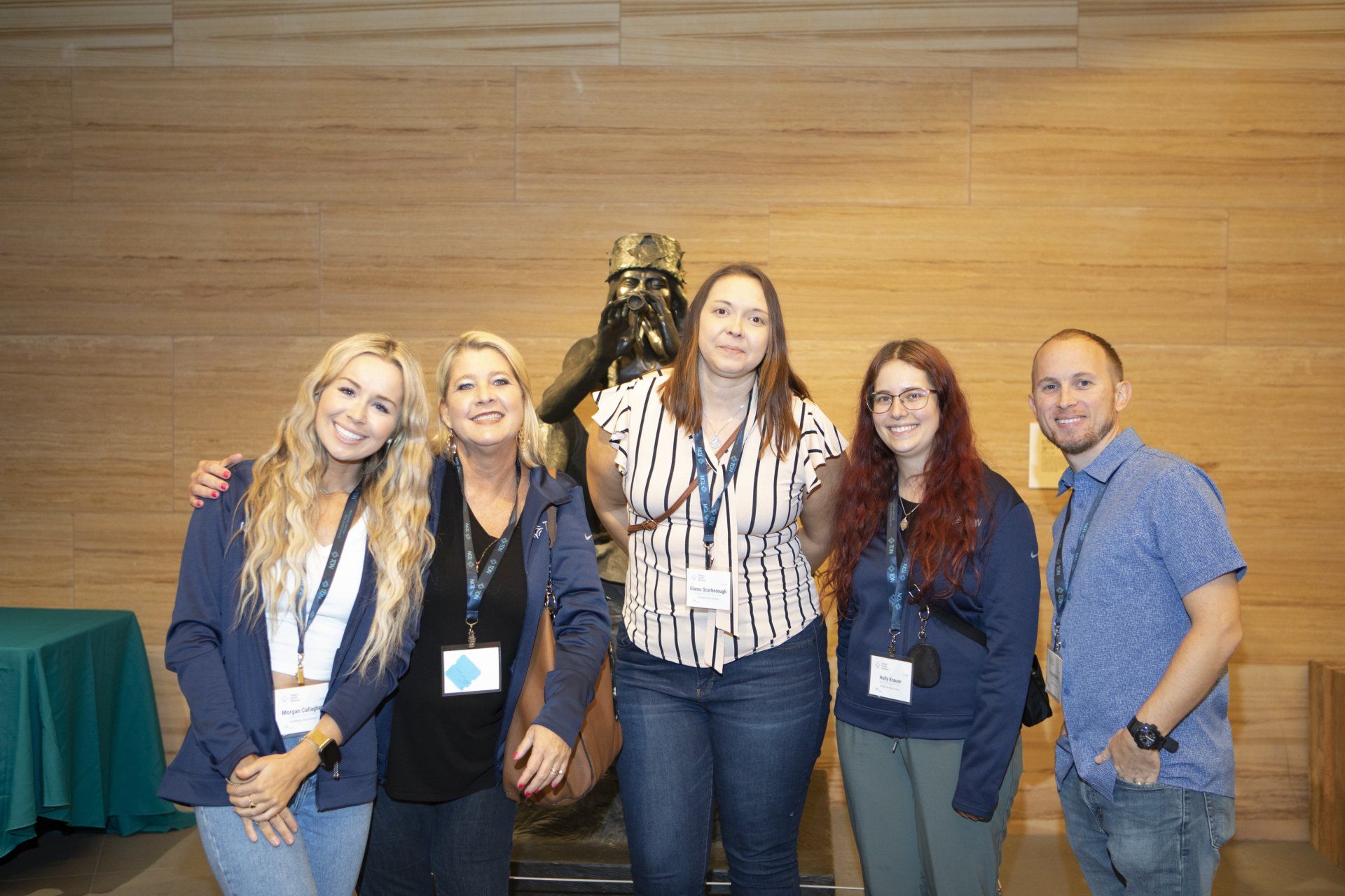A group of people are posing for a picture in front of a statue.
