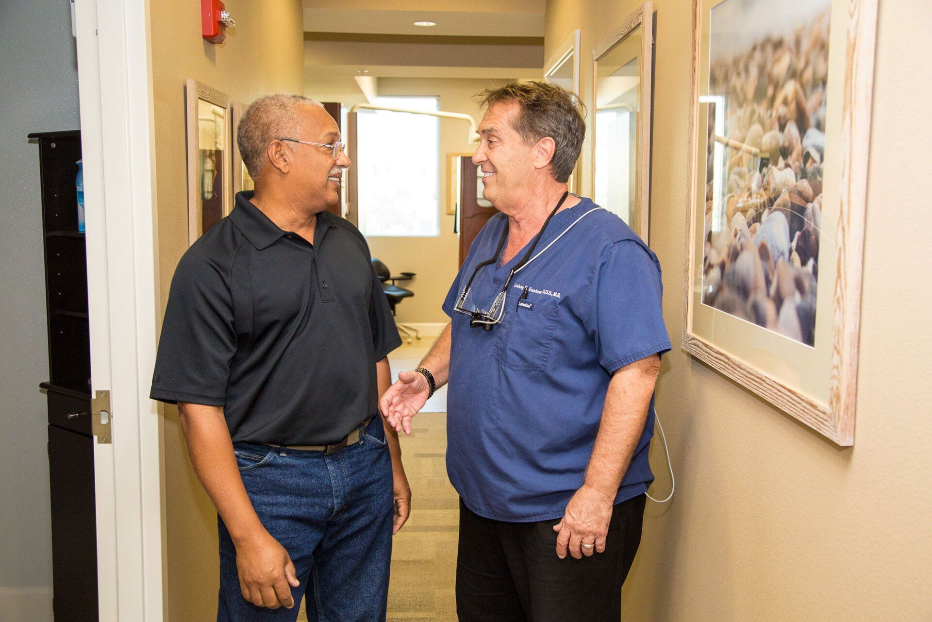 Two men are standing in a hallway talking to each other.