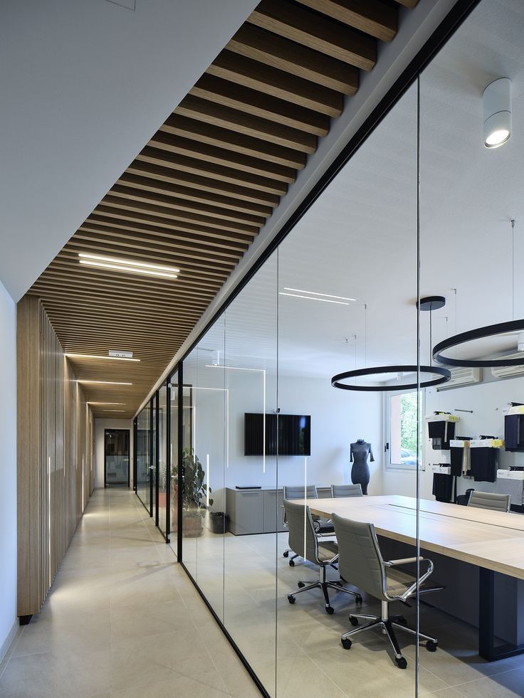 Modern office hallway with glass walls, wood accents, and recessed lighting.