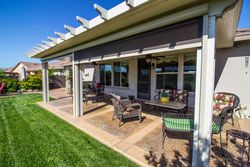 Covered patio with outdoor seating beside a green lawn and sliding glass doors