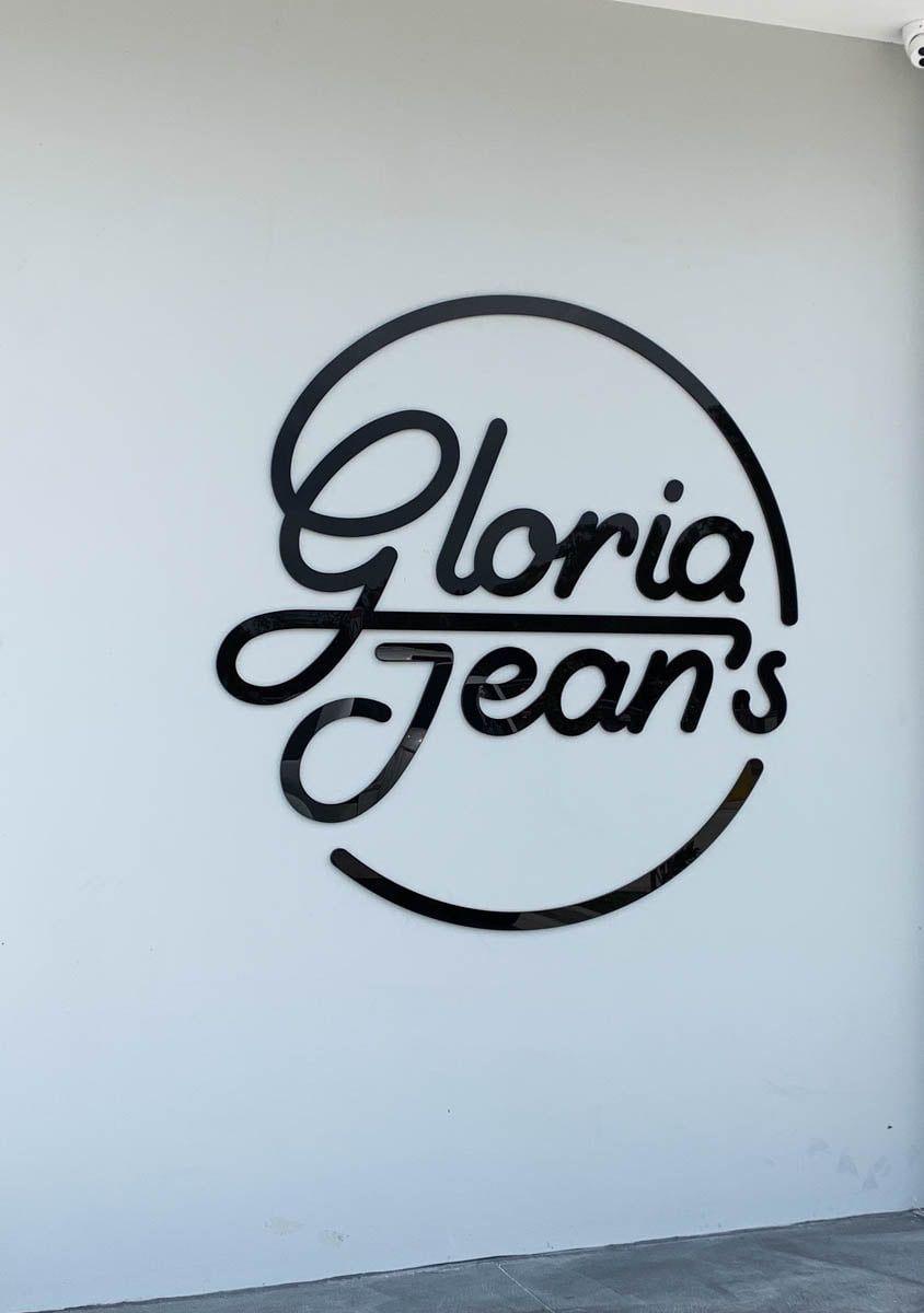 The Logo For Gloria Jeans Is Painted On A White Wall  — Solis Signs in Toukley, NSW