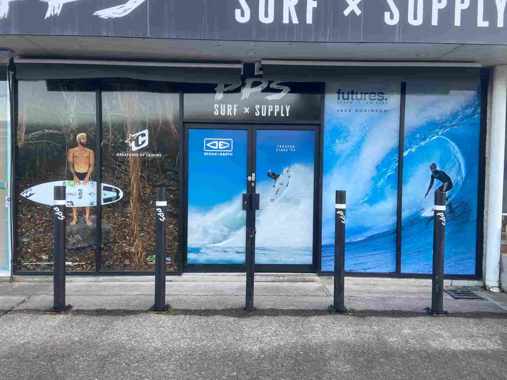 A Store Front With A Picture Of A Man Riding A Wave On A Surfboard  — Solis Signs in Toukley, NSW