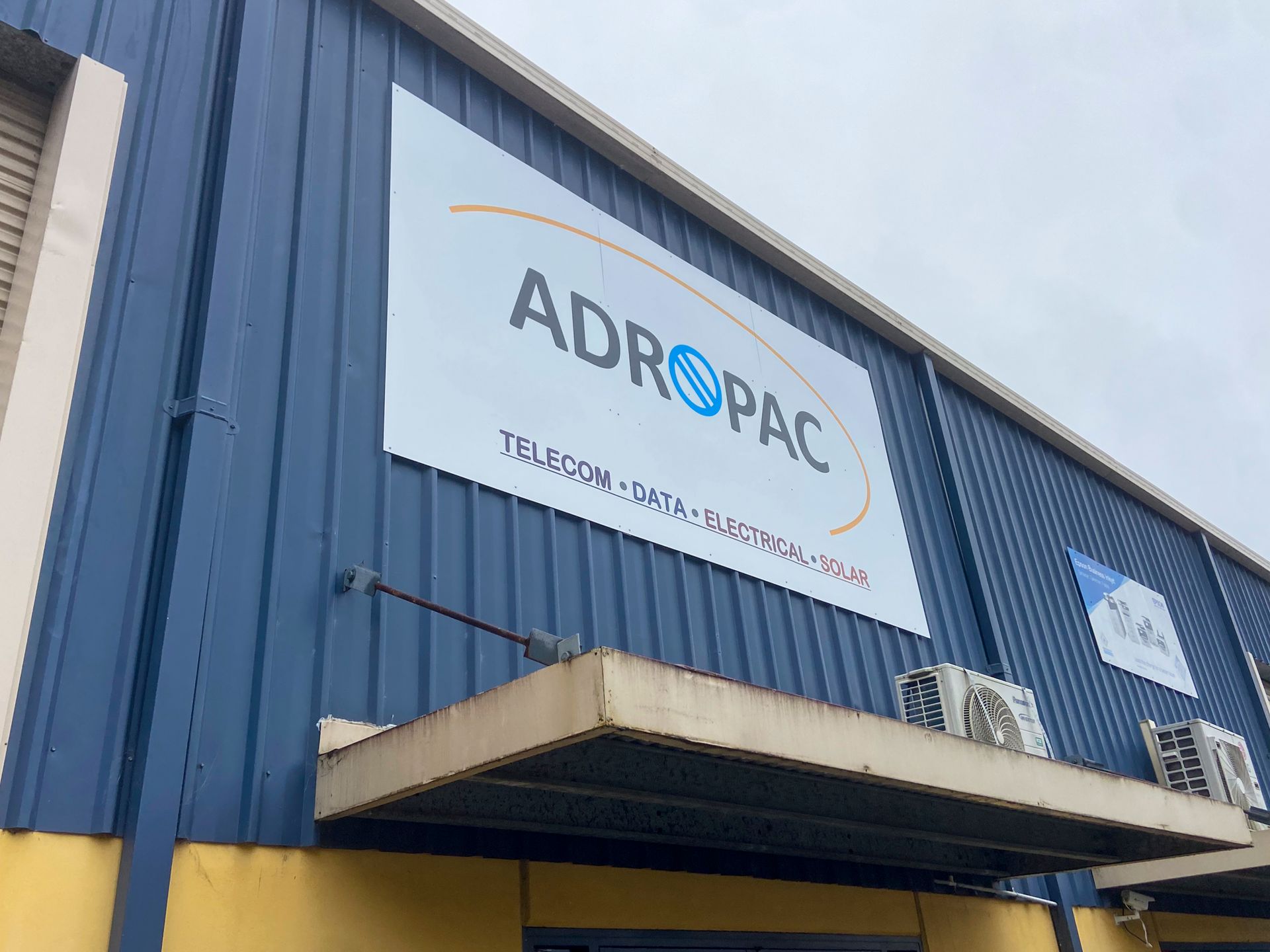 A blue building with a white sign on the side that says adropac. — Solis Signs in Toukley, NSW