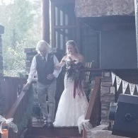 Bride and older man coming down wooden stairs during a wedding ceremony