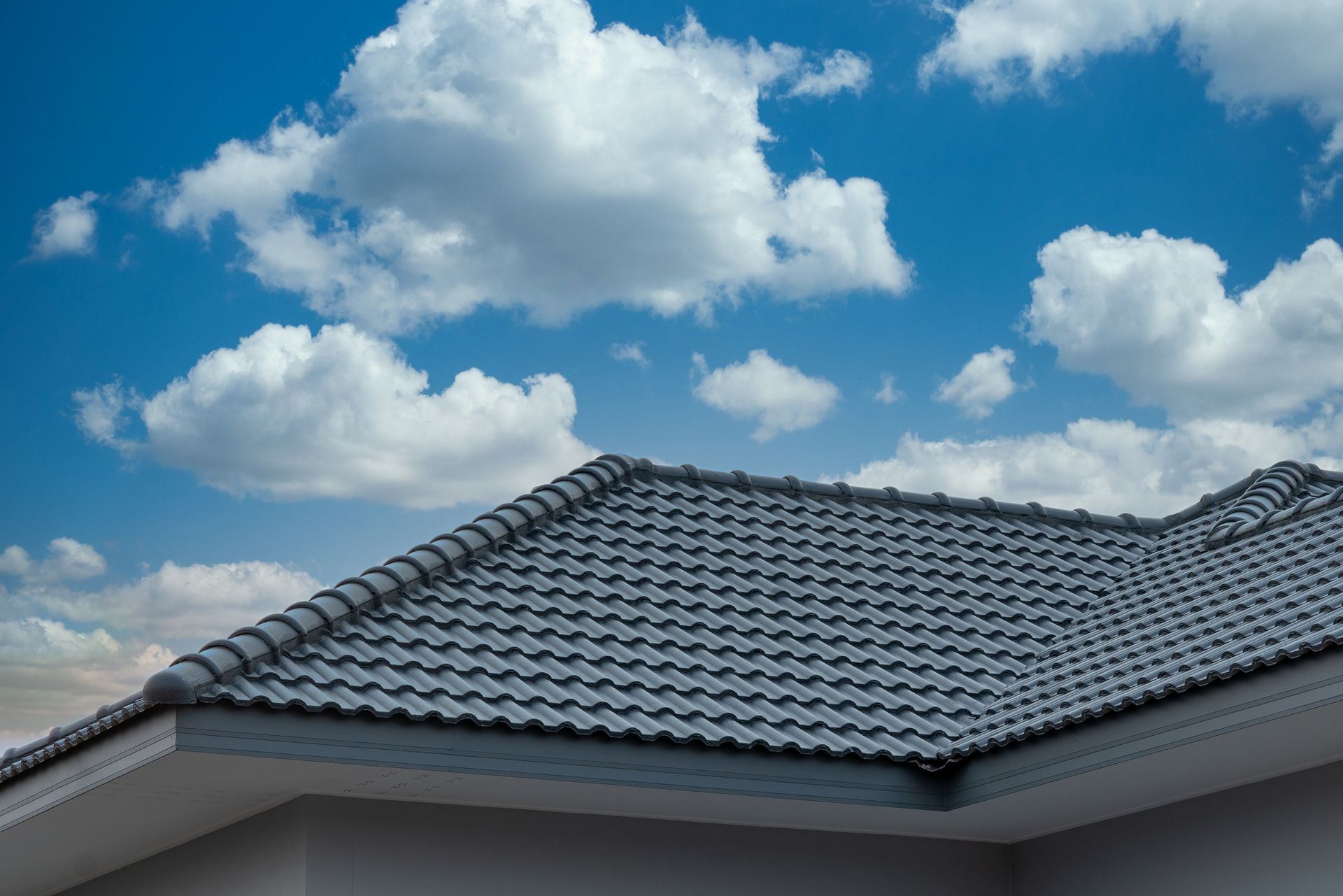 Person hammering shingles on a roof.