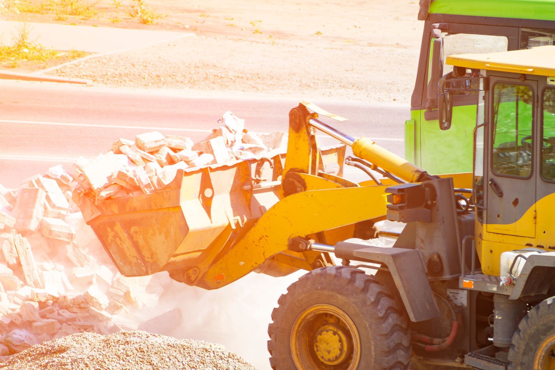 Yellow front loader hauling snow at a bright, snowy construction site
