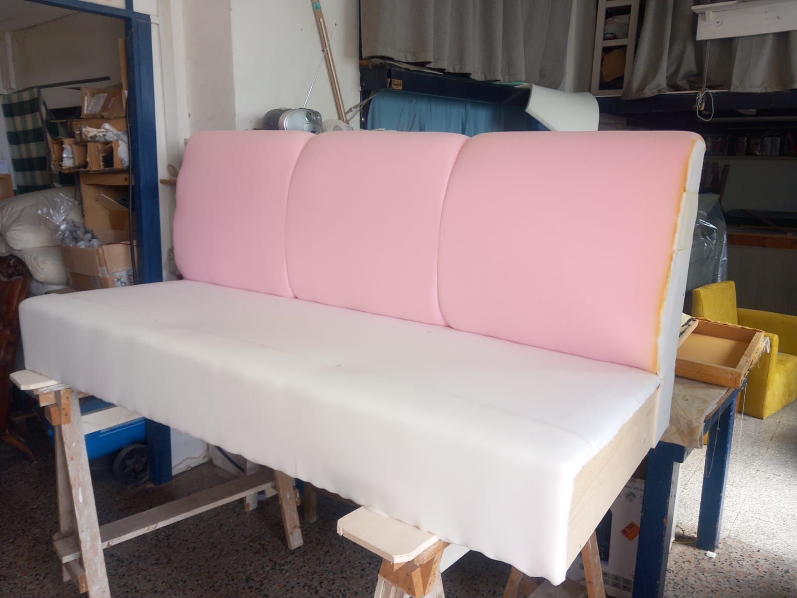 Un banco parzialmente finito in un laboratorio. Ha una seduta bianca e uno schienale rosa a segmenti.