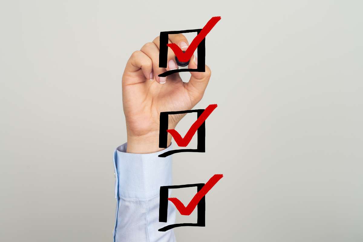 Hand checking off boxes with red checkmarks, representing completed tasks in a content audit template checklist.