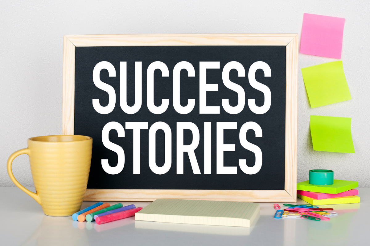 A chalkboard with the word 'Success Stories' written on it, surrounded by paper, notepads, clips, and a cup of coffee, symbolizing real success stories to inspire you.
