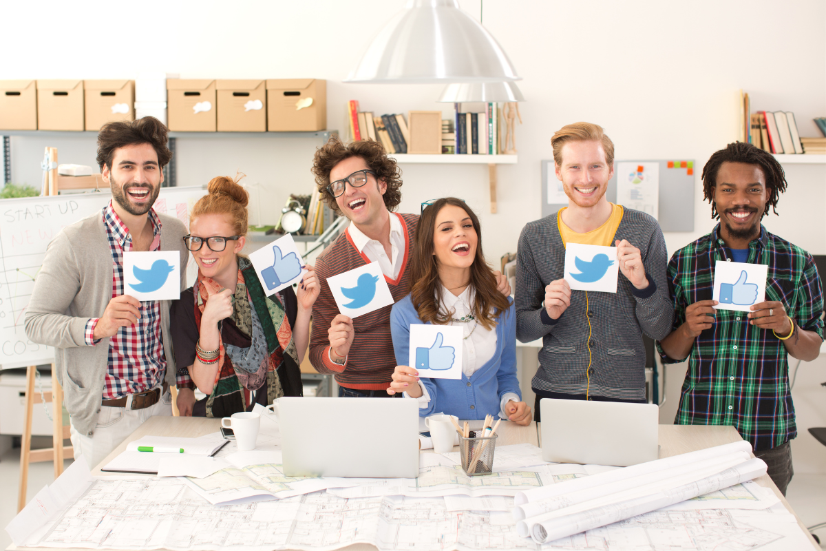 A joyful group of people holding up social media icons, symbolizing the importance of building a community at the heart of social media engagement.