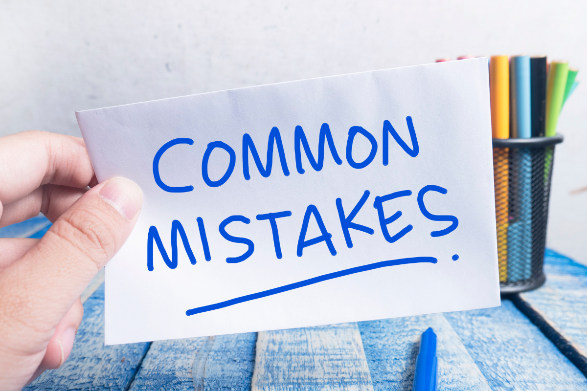 A hand holding a piece of paper with the words 'Common Mistakes' written on it, symbolizing the identification and awareness of frequent errors in a process, highlighting the importance of learning from and avoiding these mistakes for better results.