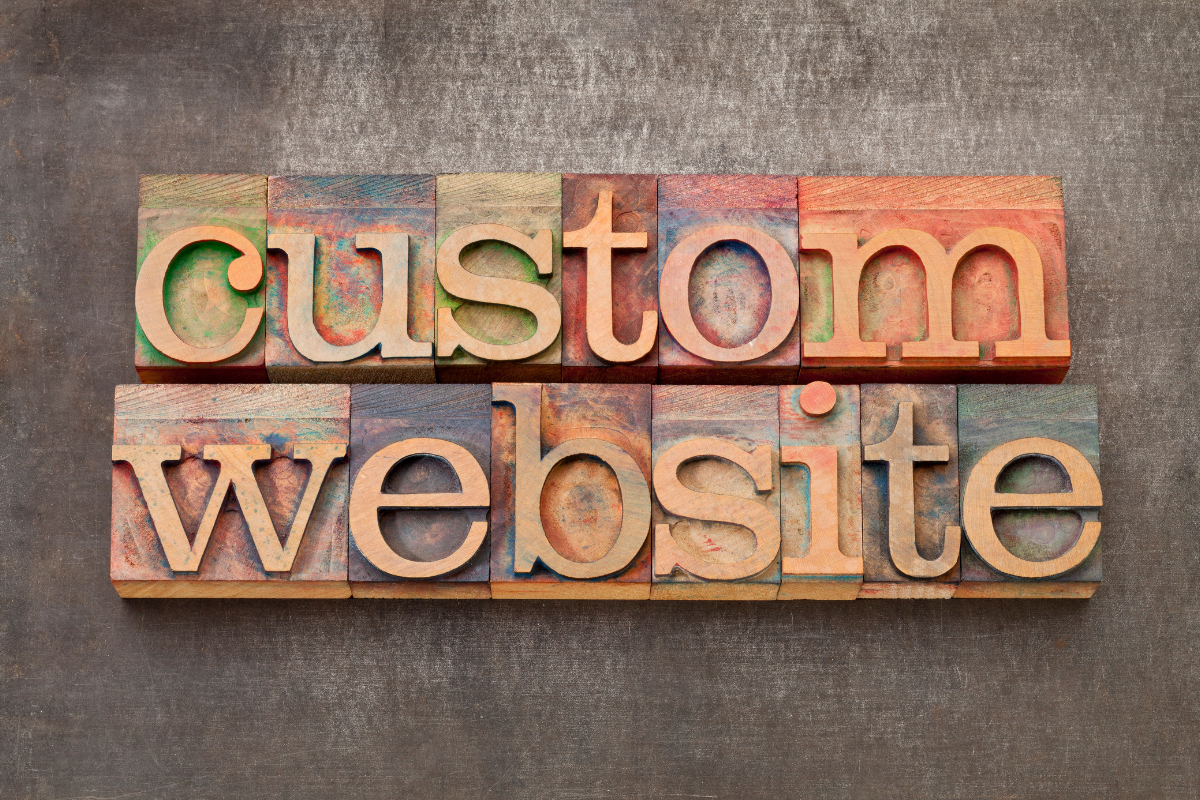 A close-up of the word 'Custom Website' engraved in wood, symbolizing the personalized and handcrafted approach to the custom web development process, emphasizing the unique, tailored solutions crafted for each client.