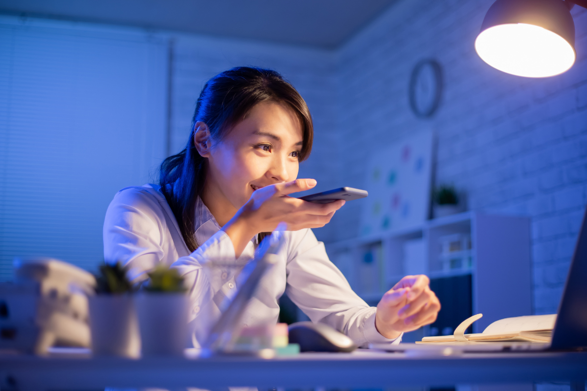 A woman using voice search on a smartphone at night, highlighting dynamic SEO trends like voice optimization and user intent focus.