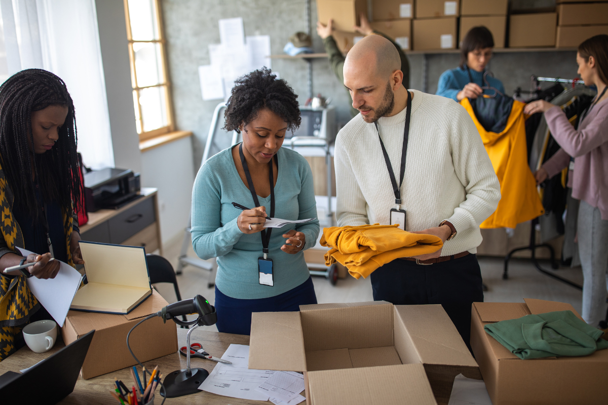 A team packing and organizing clothes for fast fashion websites, processing orders in a busy workspace with boxes and garments.