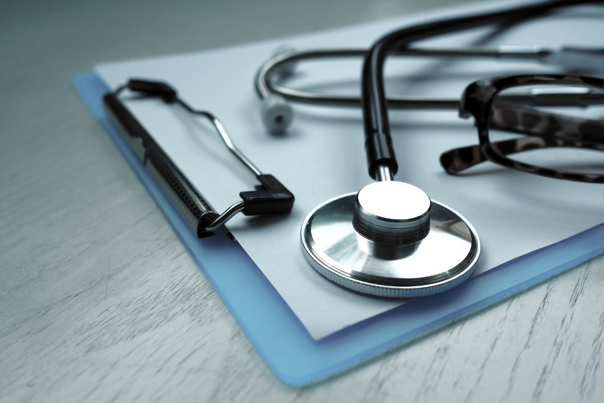 A stethoscope, clipboard with documents, and eyeglasses on a desk, symbolizing healthcare SEO.