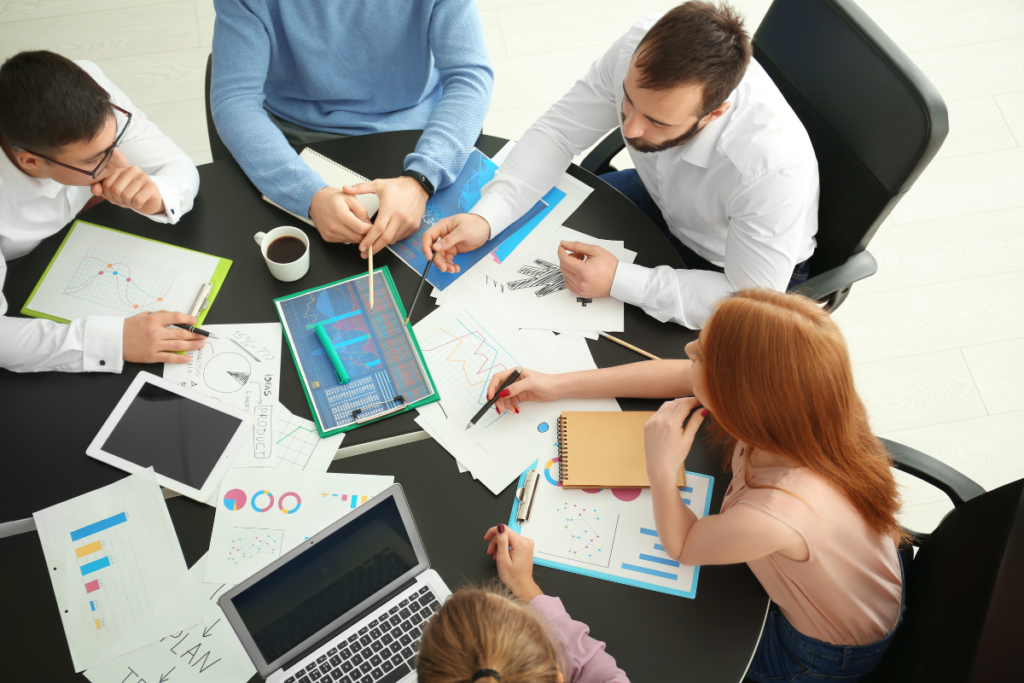 A group of SEO experts gathered around a computer screen, discussing strategies to boost visibility and drive results related to SEO conversions.