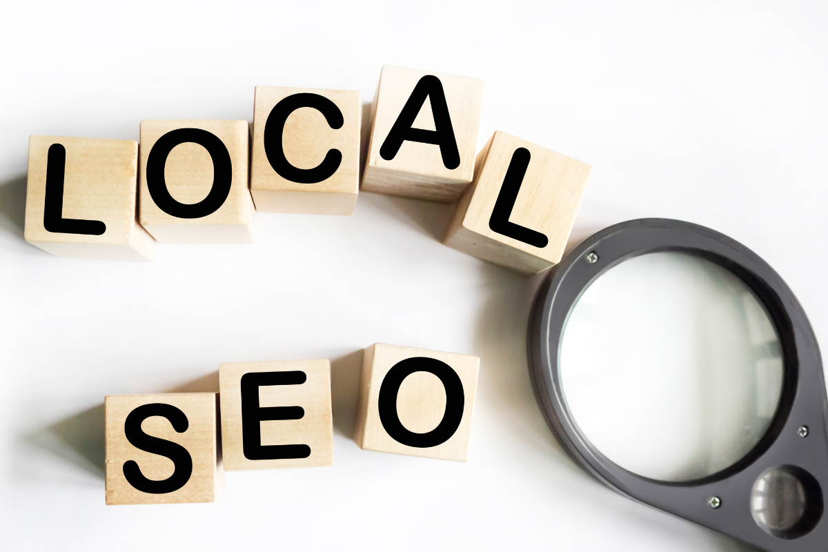 A magnifying glass positioned beside wooden blocks with the words 'LOCAL SEO' written on them.