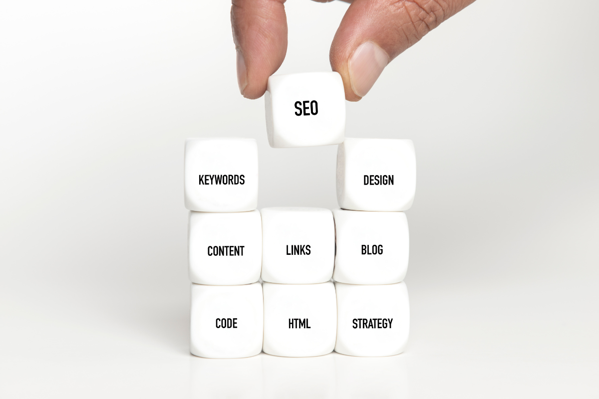 A hand stacking cubes labeled with key SEO elements such as 'Keywords,' 'Content,' 'Links,' and 'Design,' representing the foundational ranking factors of local SEO services, illustrating how these elements work together to enhance search engine visibility and drive local traffic.
