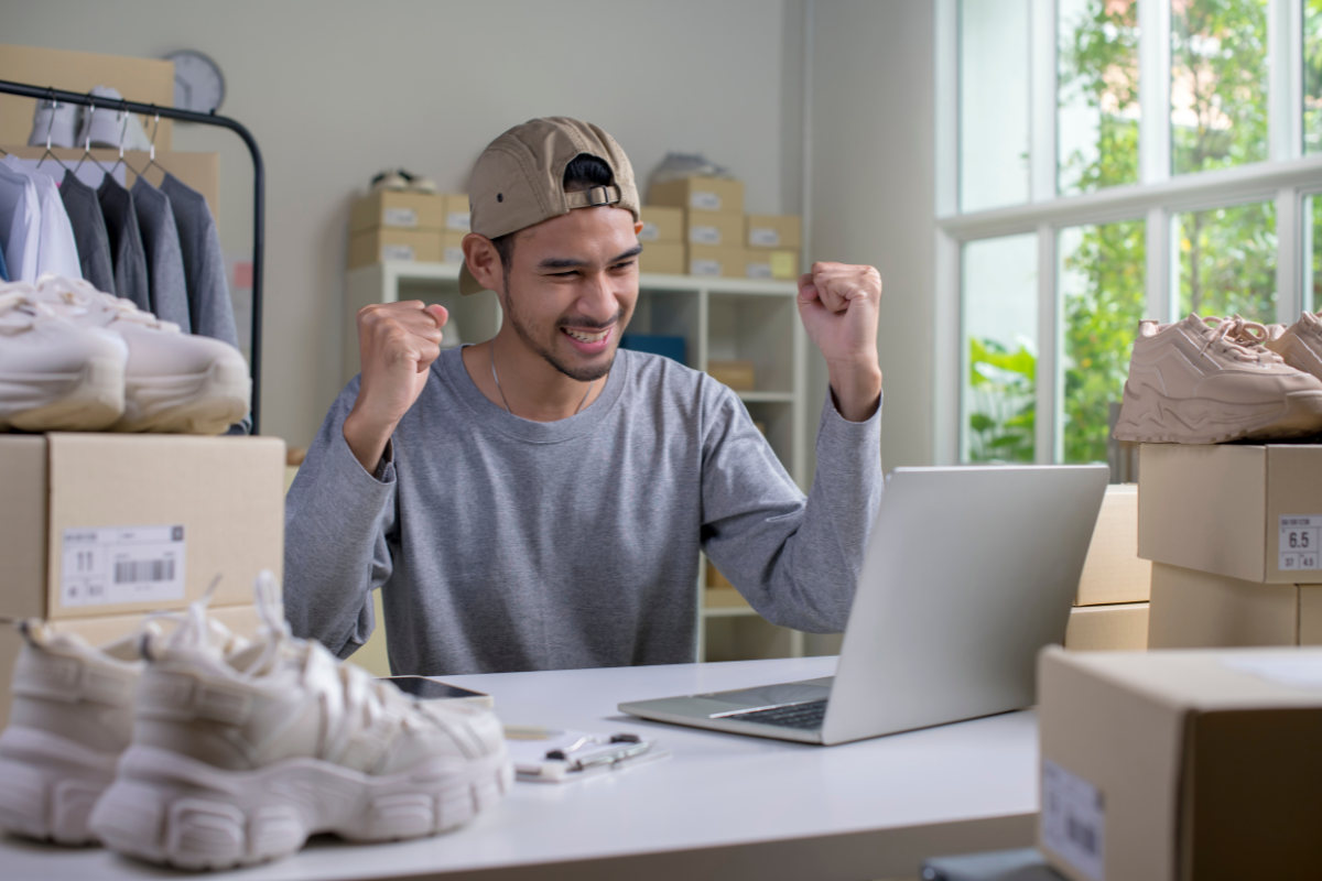 A happy e-commerce store owner smiling while reviewing sales data on a laptop, excited about optimizing their online store for success and improving eCommerce conversion with Visio SEO.
