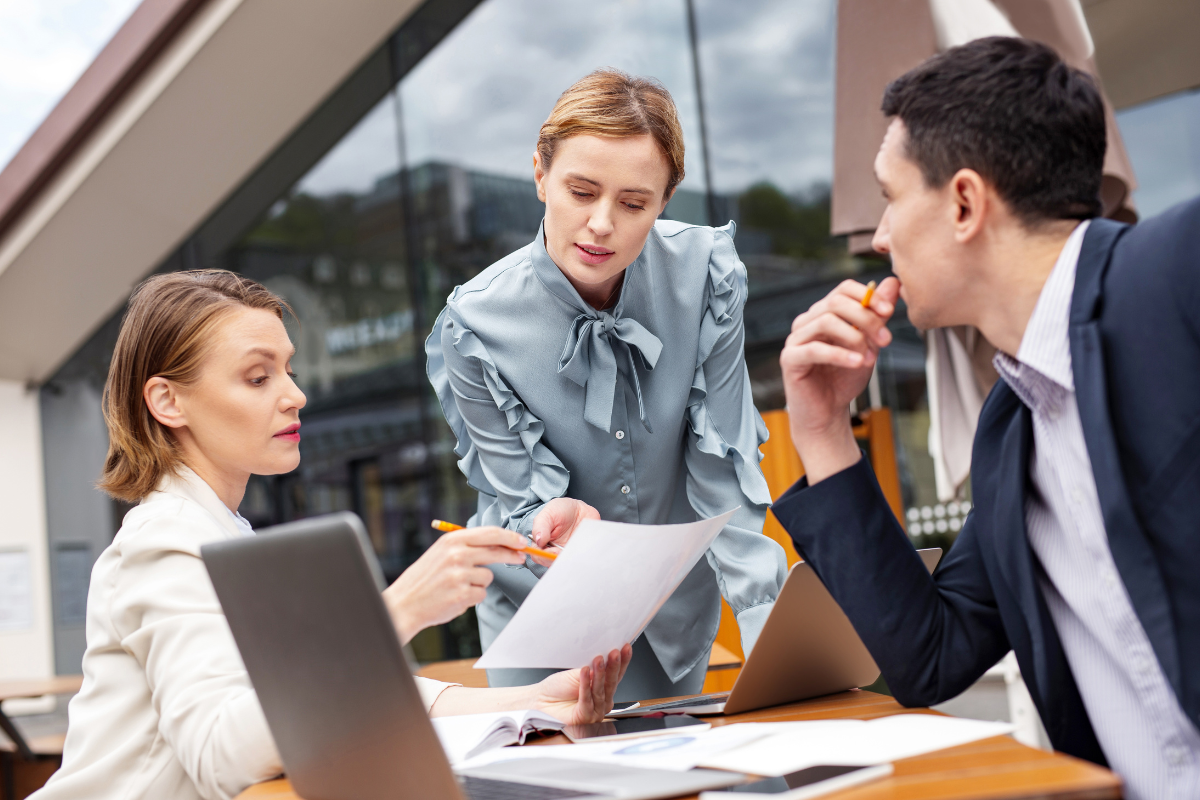 Three people engaged in a discussion, symbolizing teamwork and collaboration in web development management to effectively overcome common challenges and ensure project success.