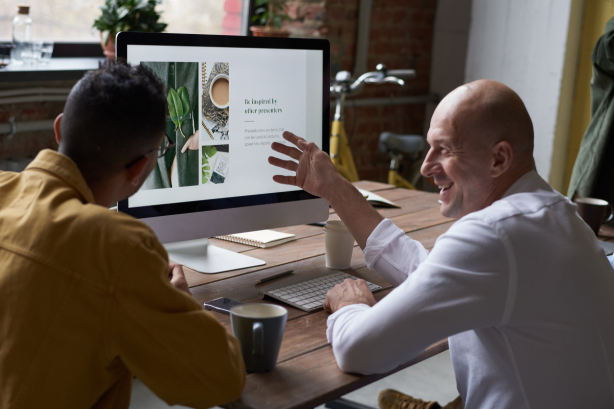 Two people happily discussing in front of a computer, representing the collaboration and success achieved by partnering with Visio SEO for expert web development management solutions.