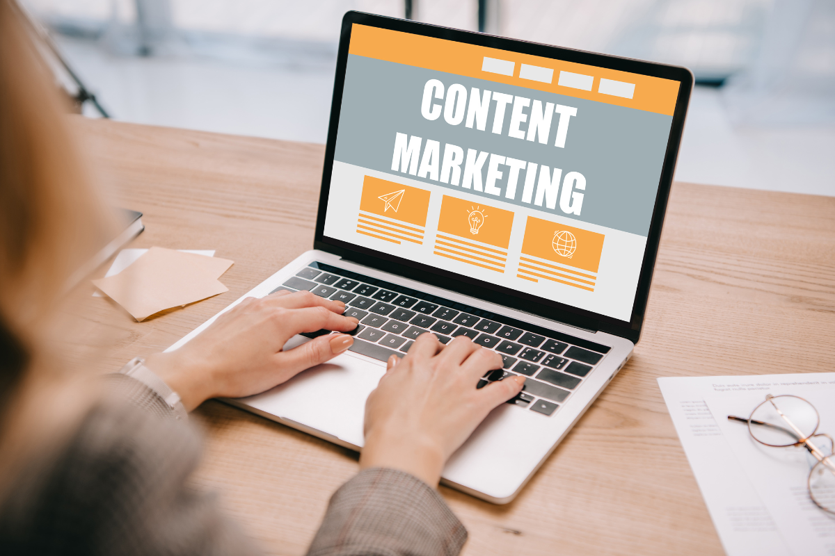 A person typing on a laptop displaying 'Content Marketing' with icons on the screen, representing digital marketing efforts.