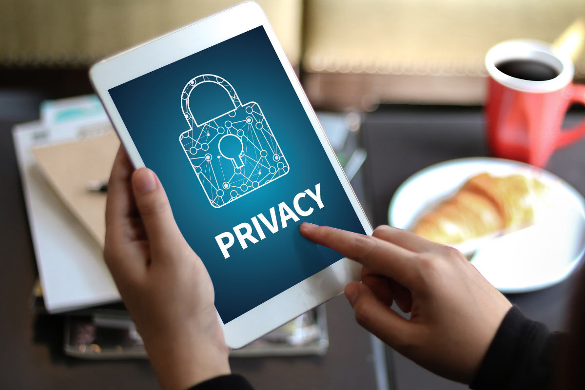 A person using a tablet displaying a privacy lock icon and text, emphasizing digital security and data protection.