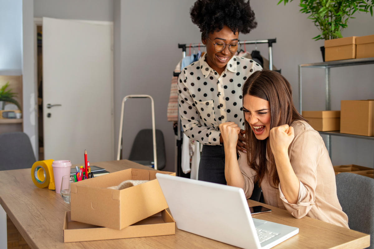 Two excited women celebrating success in their small business, symbolizing the impact of small business reputation management.