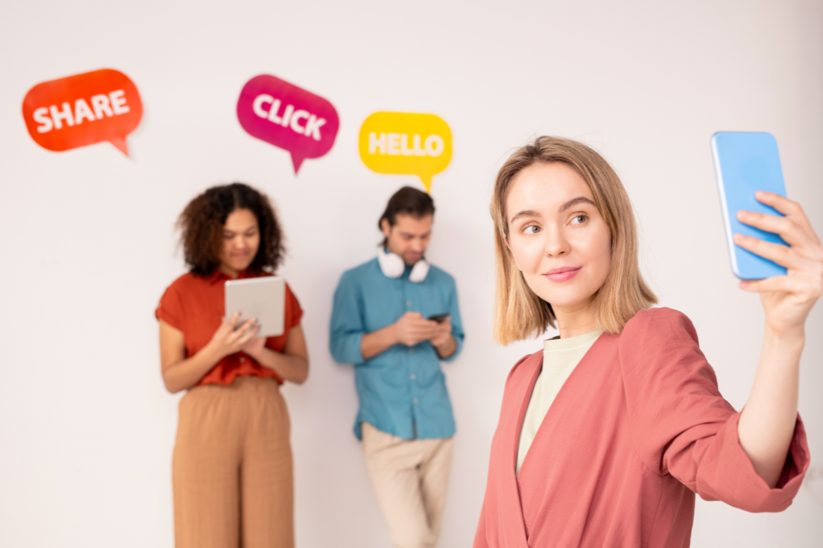 A woman taking a selfie with a group of people in the background, surrounded by social media engagement icons like share, click, and hello, highlighting the importance of social media engagement.