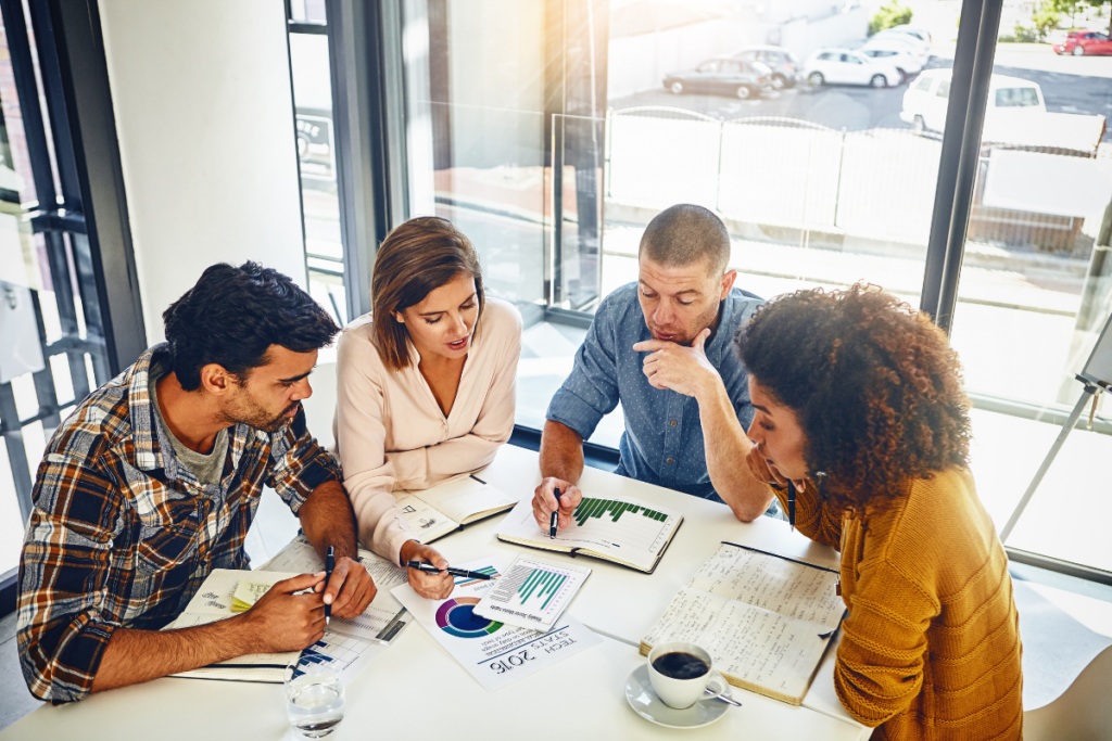 A group of people seated around a table, discussing average SEO conversion rates while pointing to a graph that highlights key trends and insights.