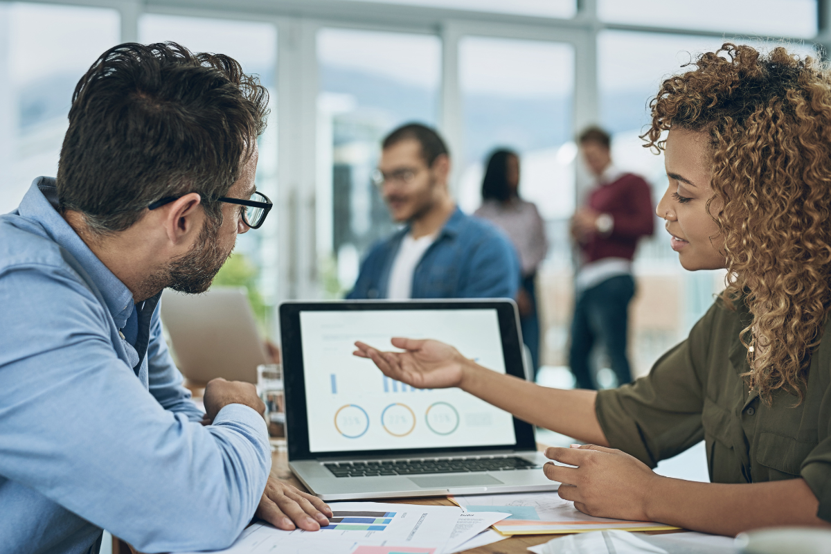 A woman presenting campaign projects to a colleague, illustrating various types of pay-per-click (PPC) campaigns in effective PPC management.