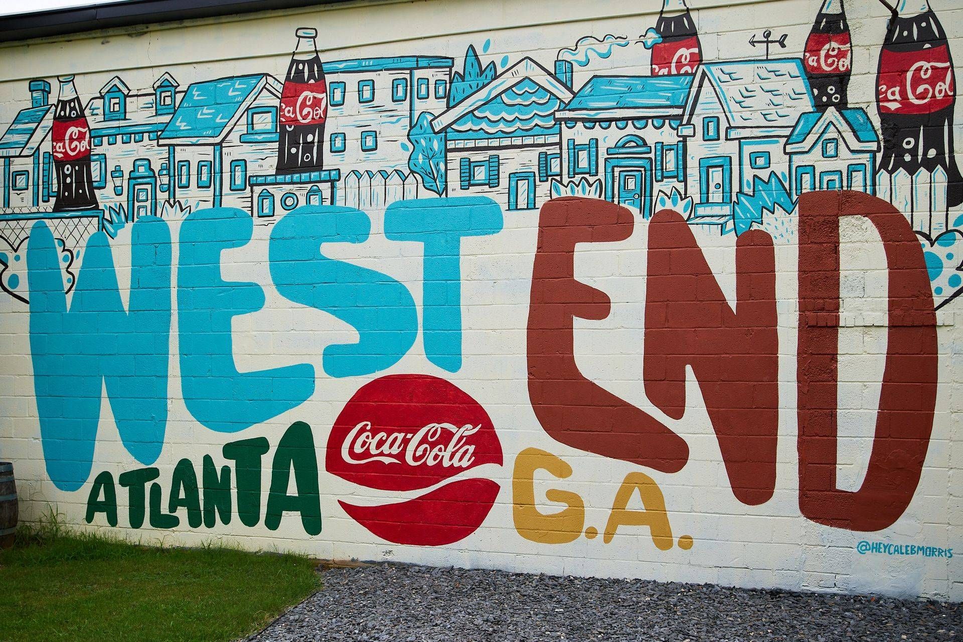 Mural reading “WEST END ATLANTA G.A.” in blue and brown with a Coca-Cola logo on a brick wall