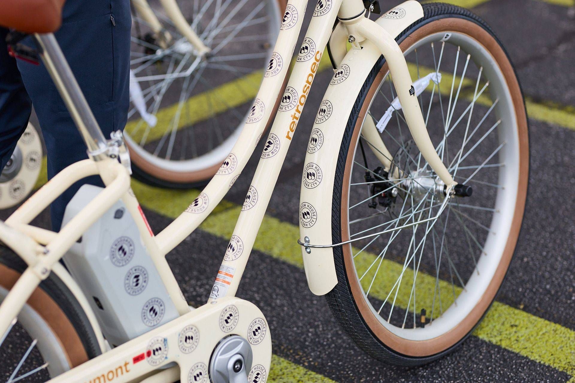 Bicycles parked on a wet street, showing white frames and orange-rimmed wheels near a yellow line