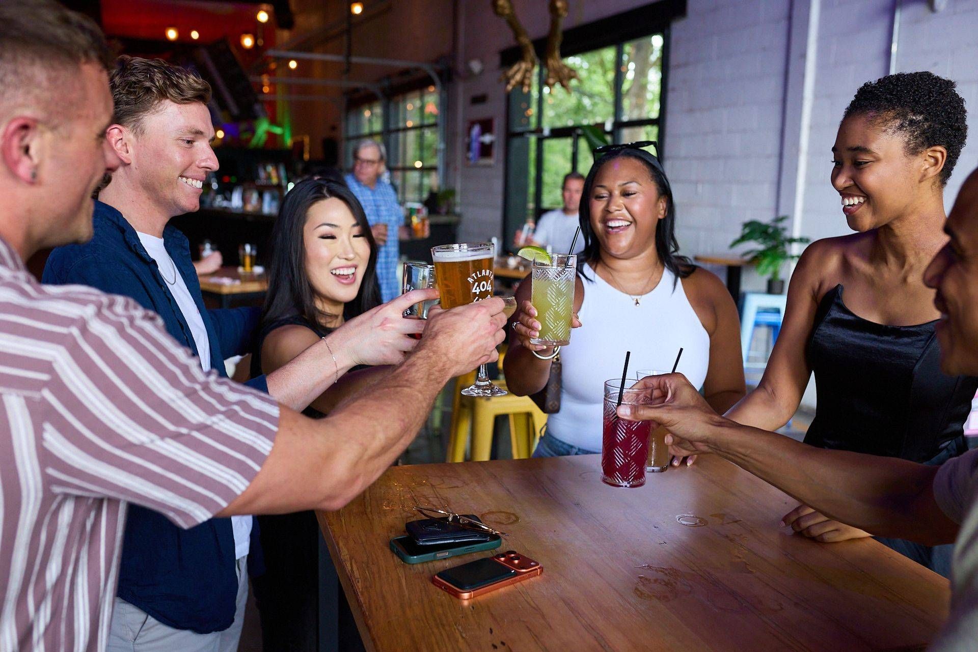 Friends smiling and raising glasses around a table in a lively bar or café