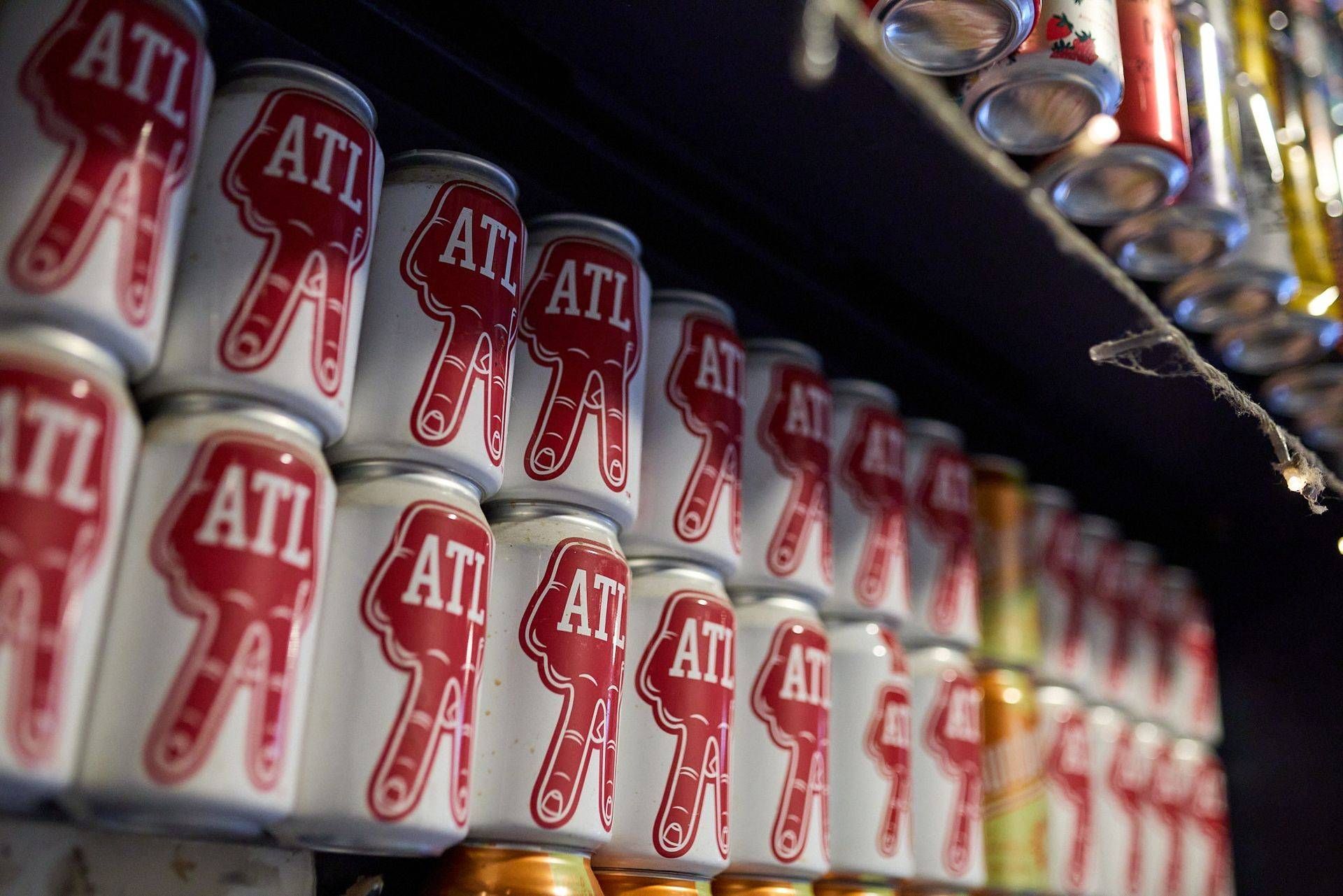 Rows of white cans with red “ATL” logos on a shelf, viewed at an angle