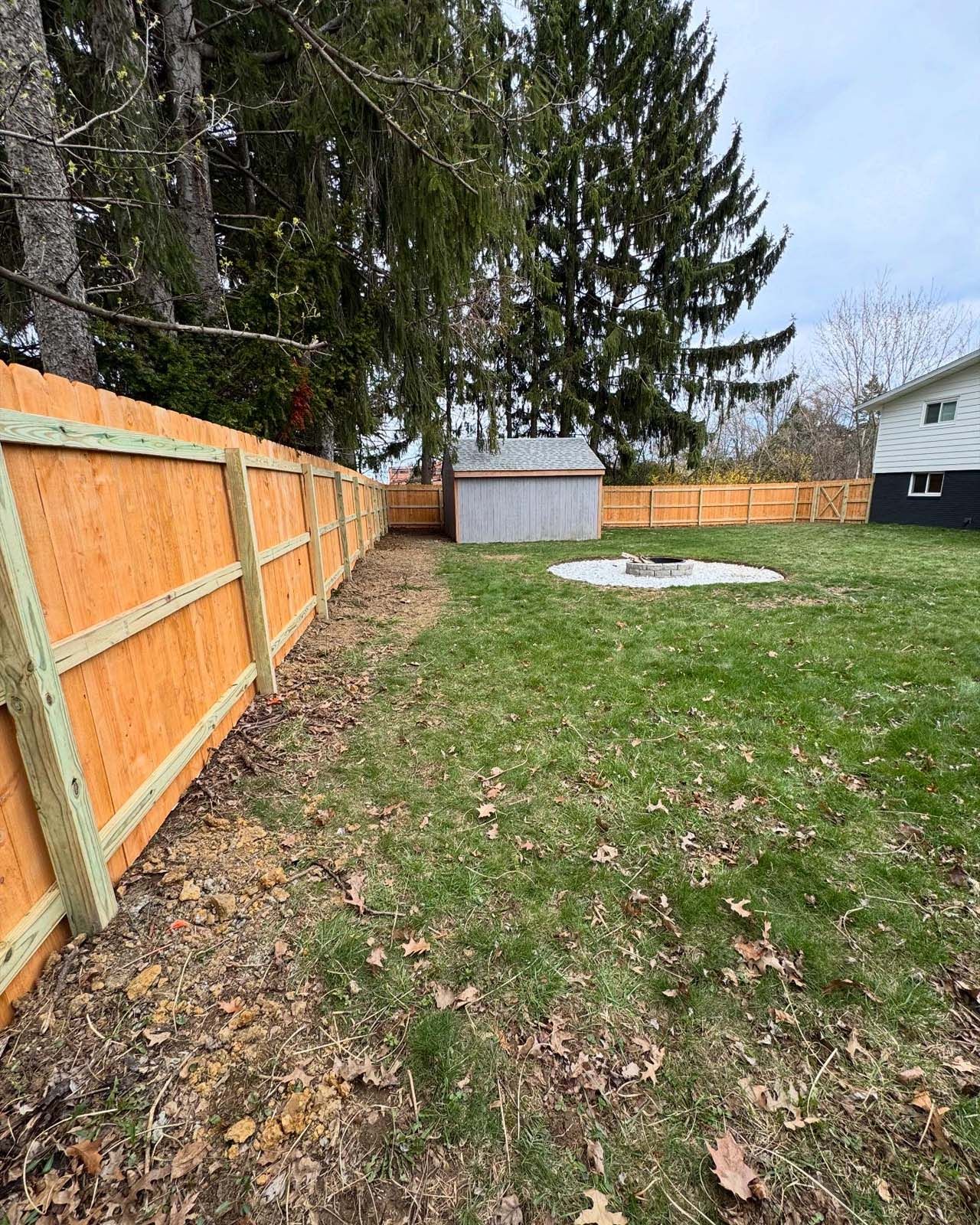 A wooden fence is surrounding a lush green yard.