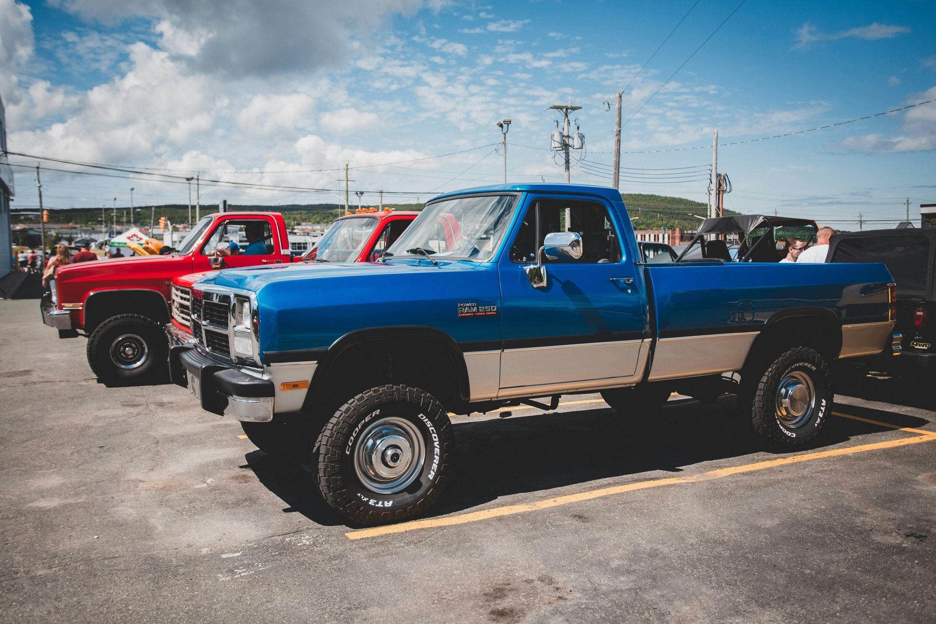 A blue truck is parked next to a red truck in a parking lot.