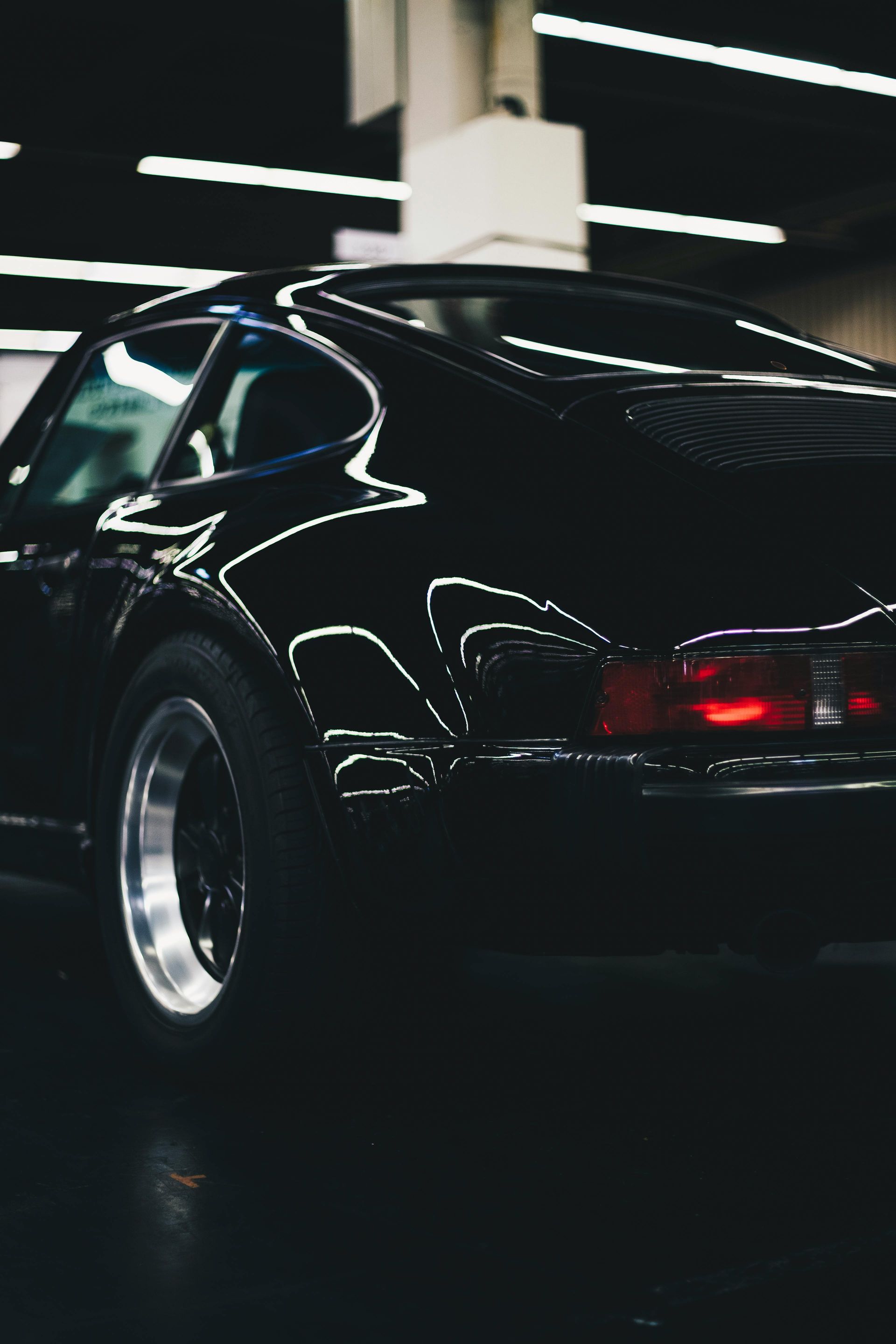 A black car is parked in a dark room